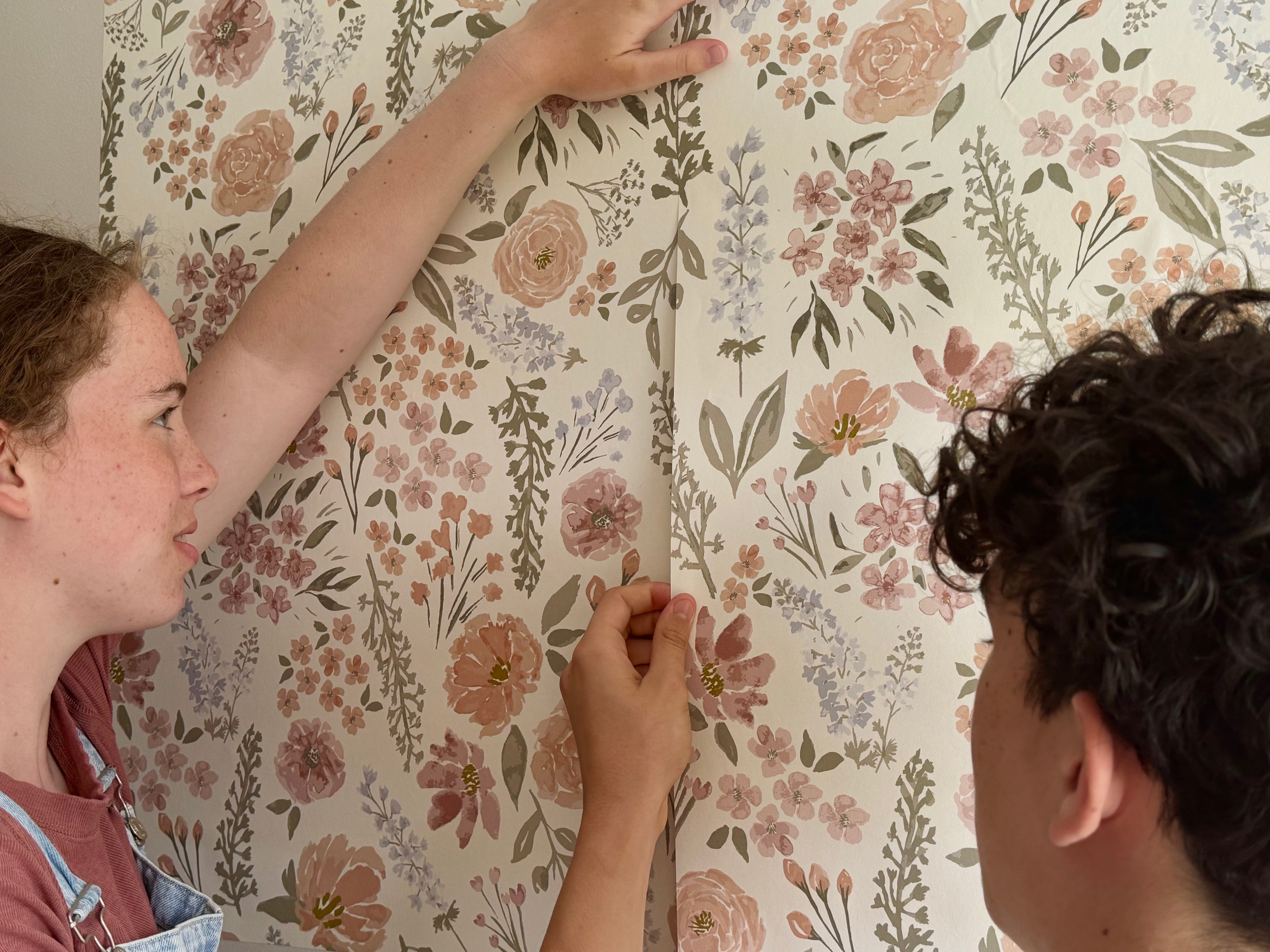 Two people inspecting floral wallpaper