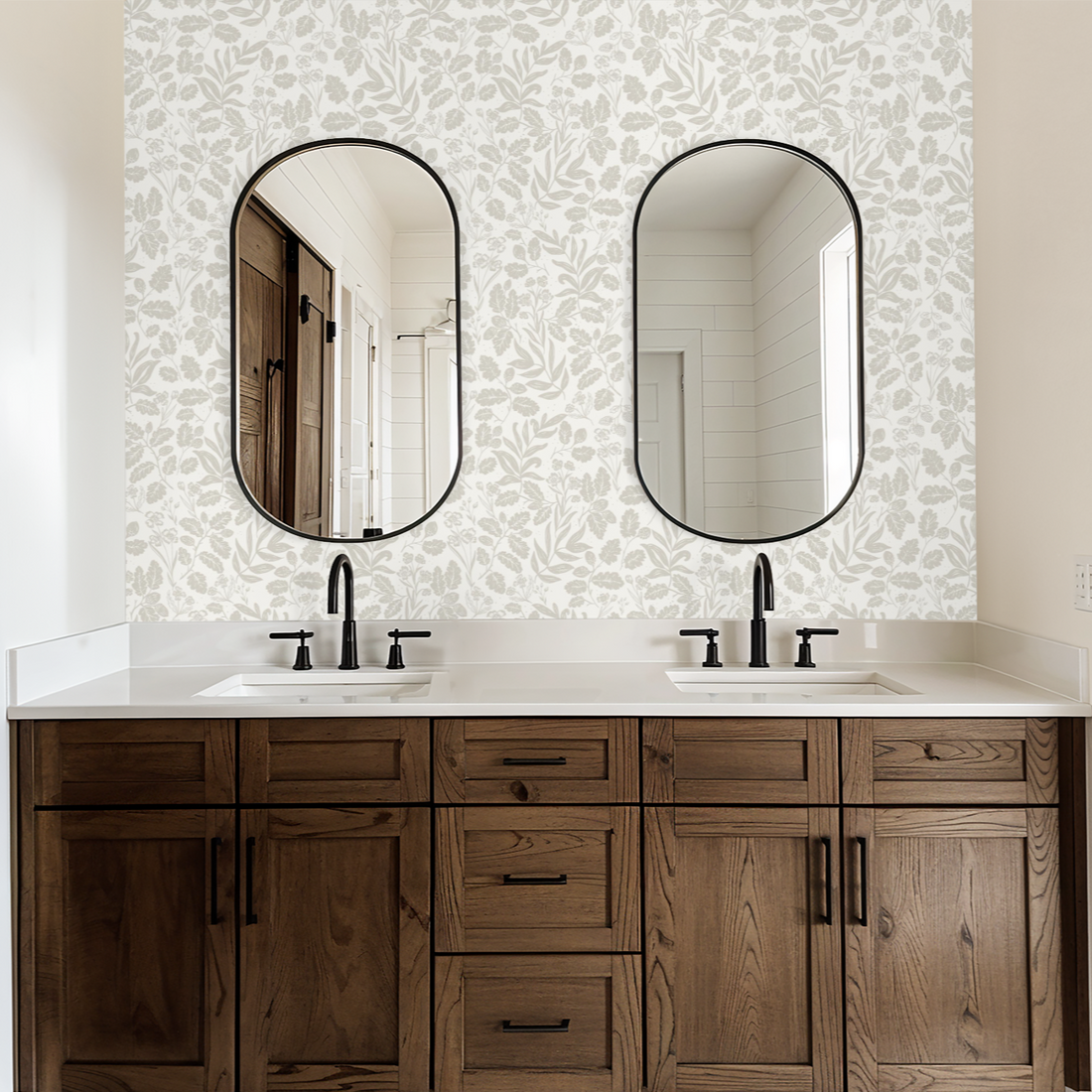 Bathroom vanity with two oval mirrors and floral wallpaper.