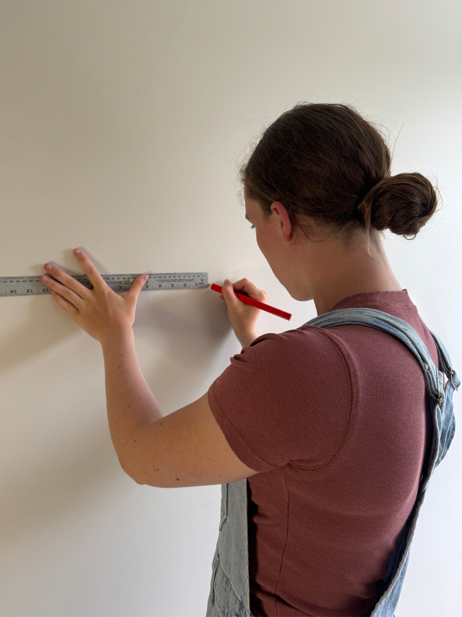 Person measuring a wall with a ruler and pencil
