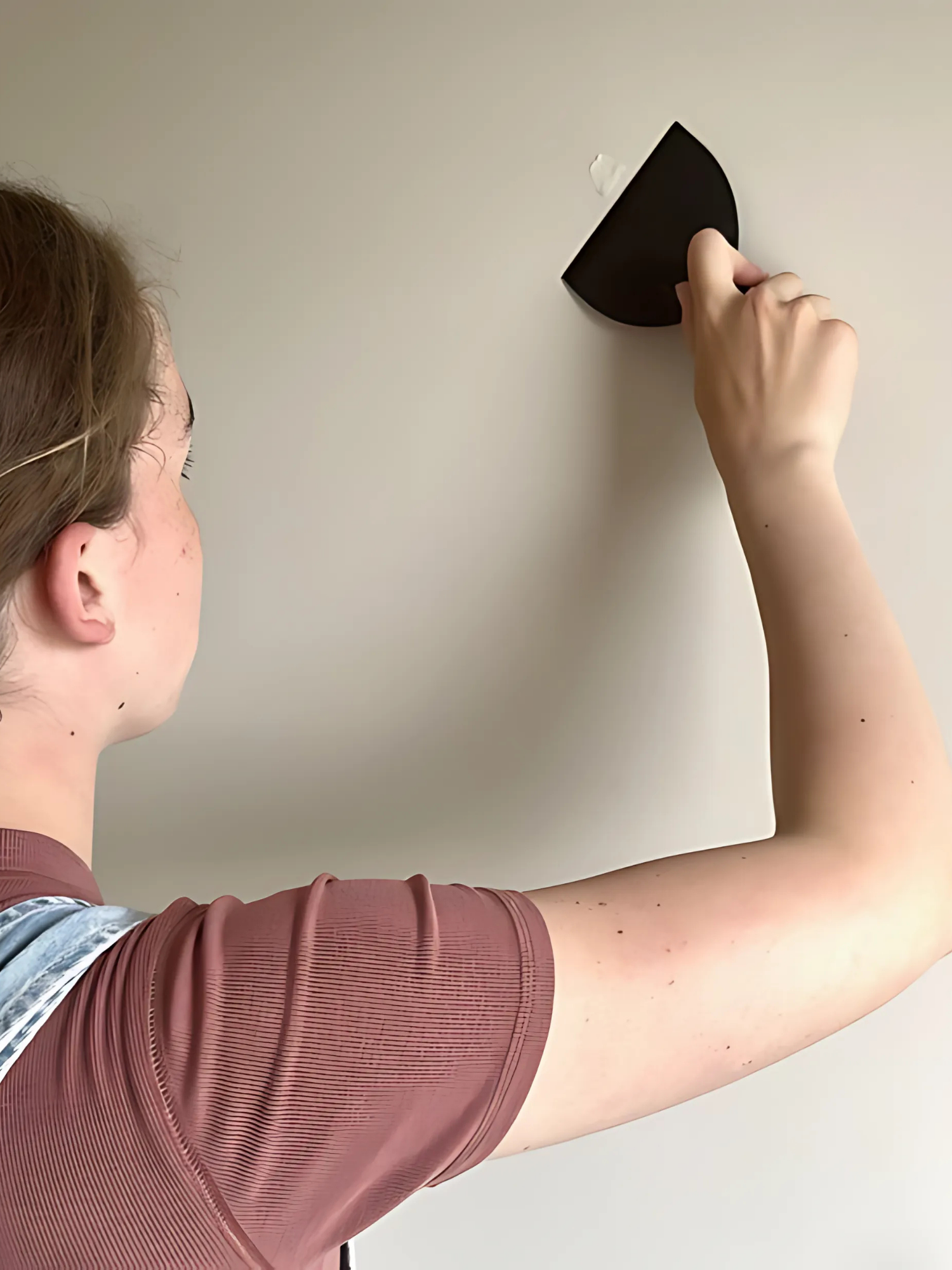 Person applying a black square object to a white wall