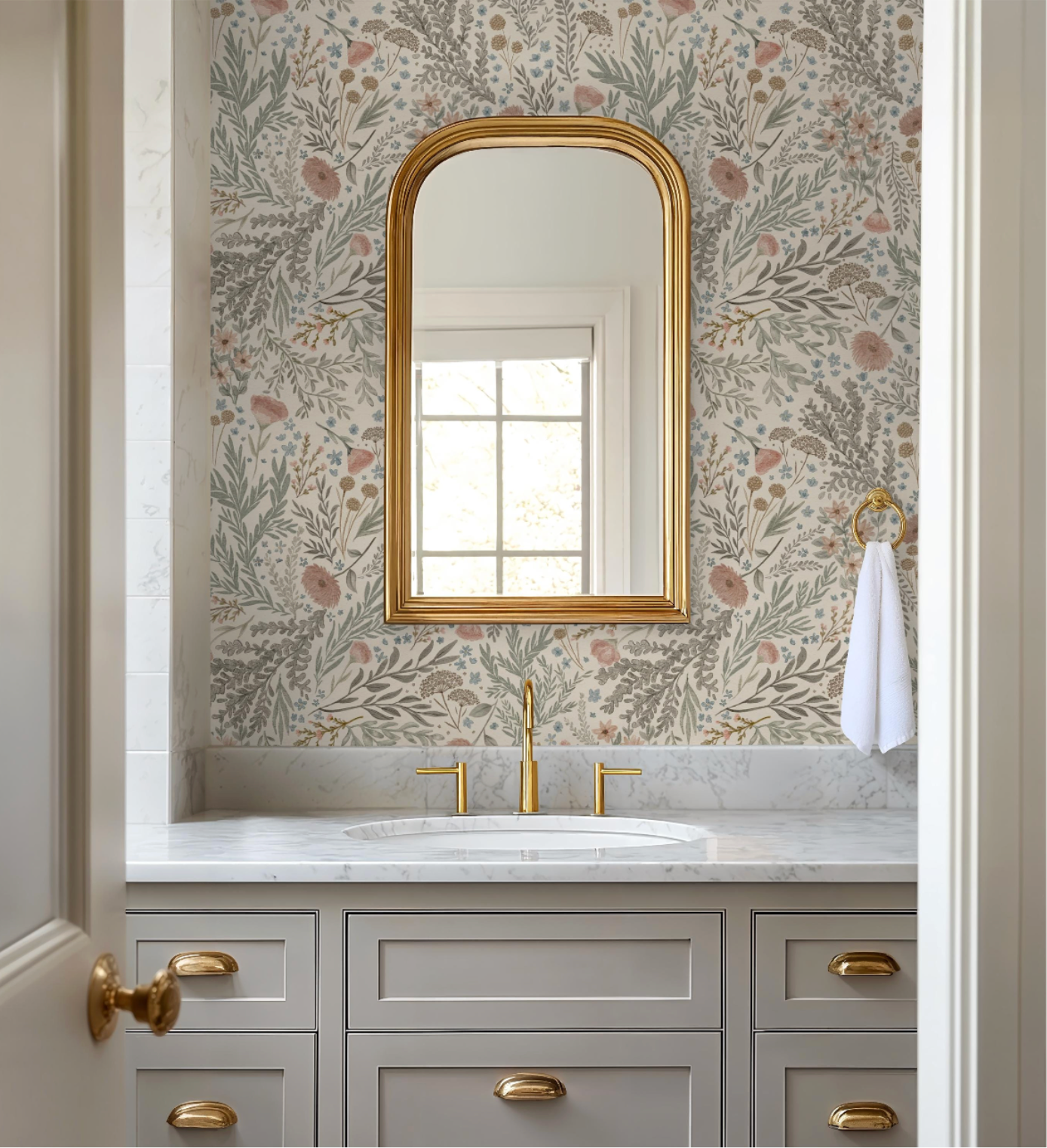 Brontë Woodland Fauna floral wallpaper in an elegant bathroom with brass fixtures, marble countertop, and arched gold mirror.
