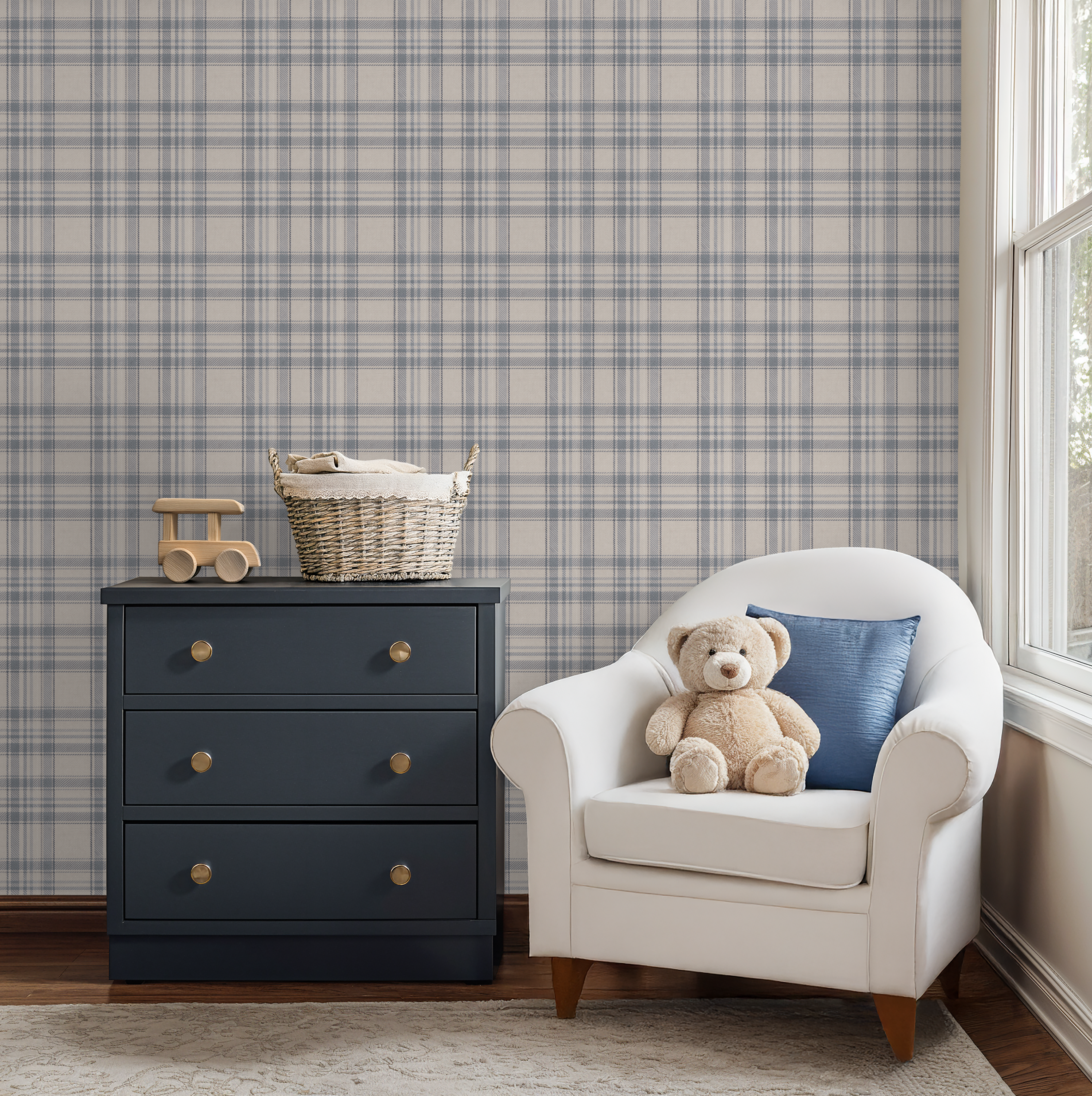 Nursery room with Tweed Plaid - Navy Blues wallpaper, navy dresser, and white chair with teddy bear and pillow.