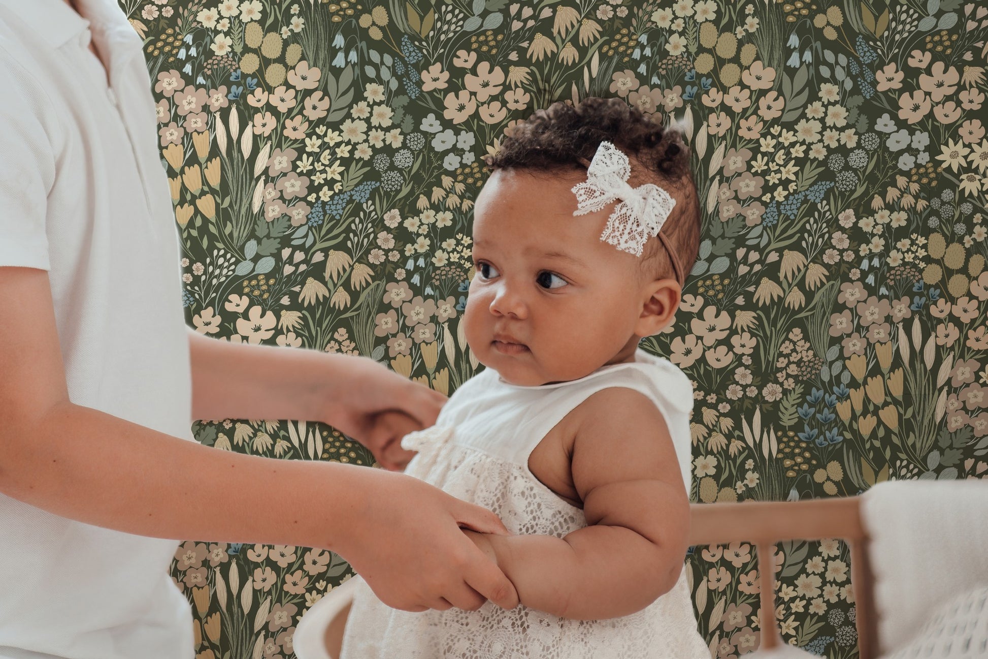 Baby nursery with olive green wildflower wallpaper featuring soft floral pattern, styled with neutral decor and vintage-inspired nursery elements.