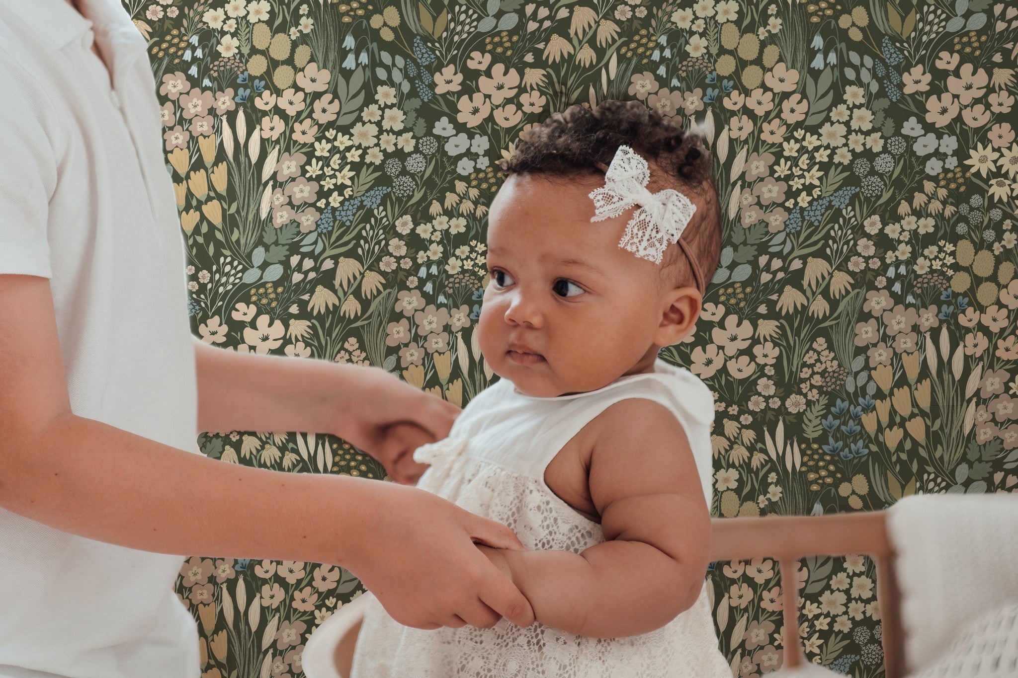 Baby nursery with olive green wildflower wallpaper featuring soft floral pattern, styled with neutral decor and vintage-inspired nursery elements.