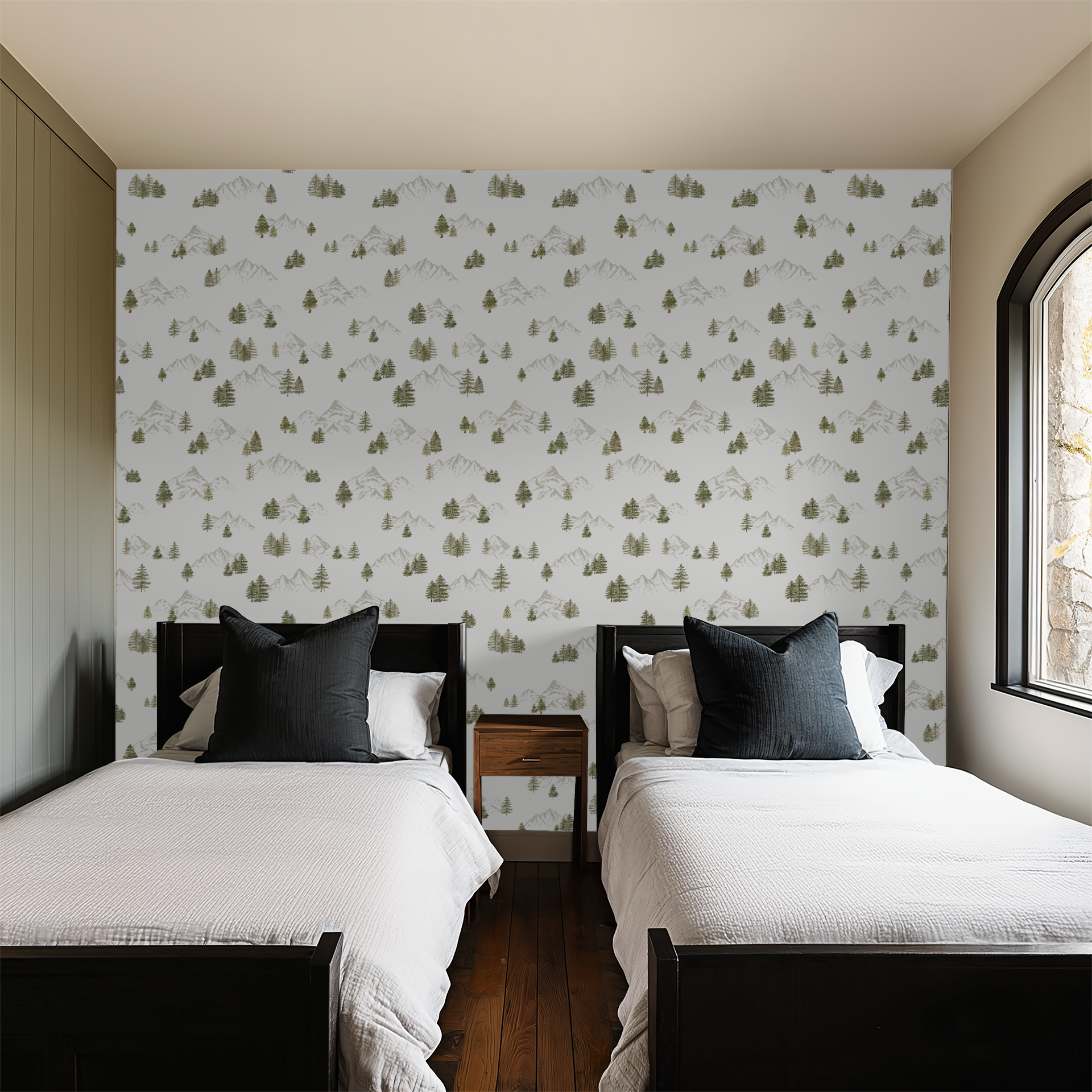 Two beds in a bedroom with forest mountain patterned wallpaper and a window.