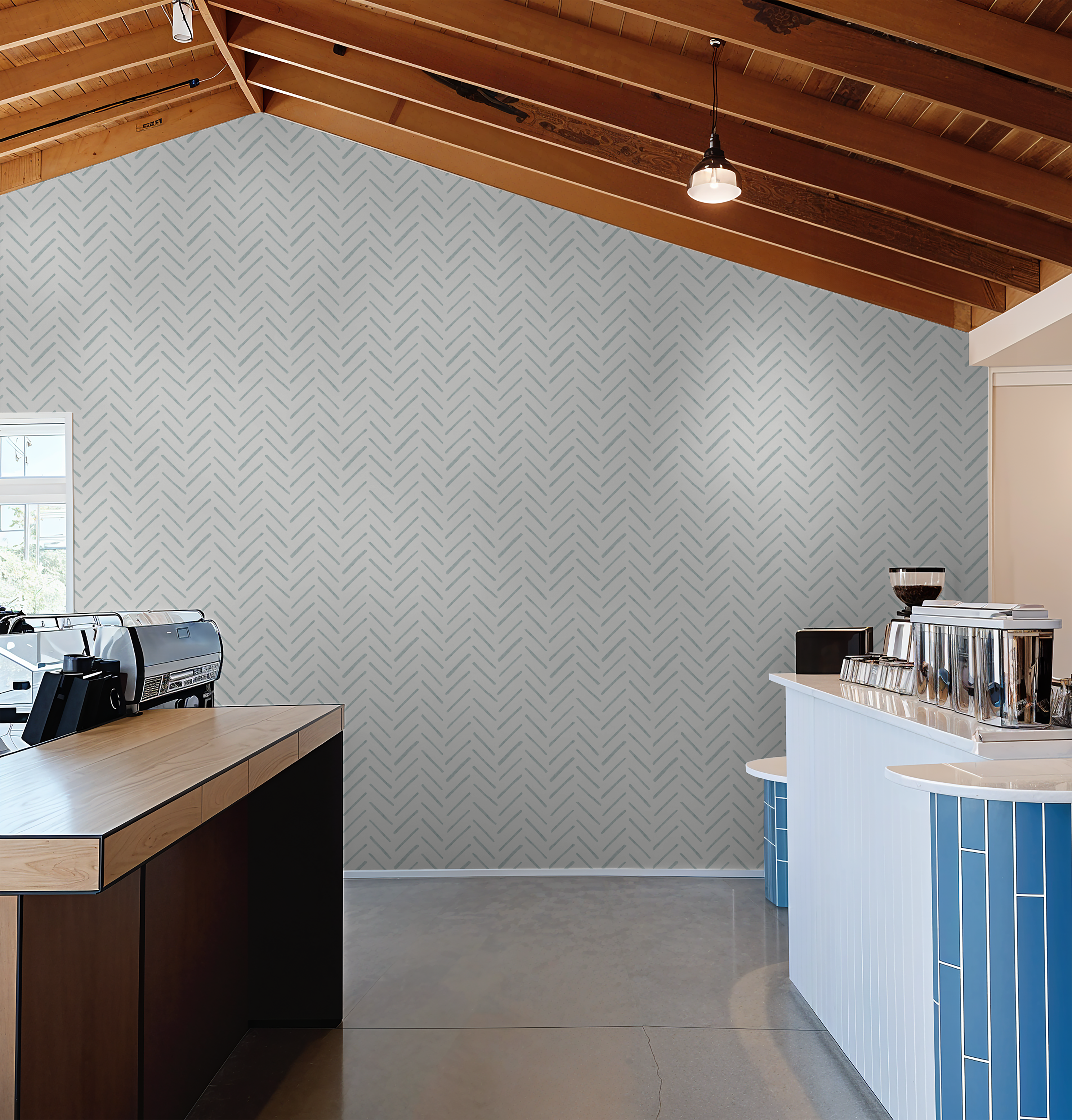 Blue watercolor herringbone wallpaper as an accent wall in a modern coffee shop with wood beams and barista counter.