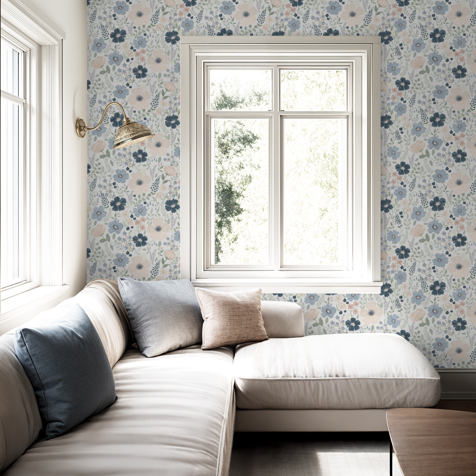 Anemone floral wallpaper in navy and blush featured in a bright living space with a white sectional and soft blue pillows.