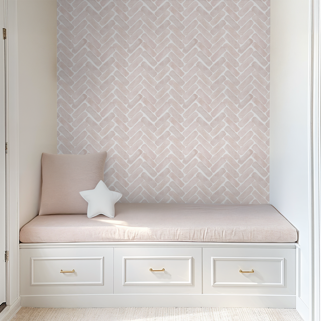 Blush pink watercolor herringbone wallpaper behind a built-in reading nook with blush cushions and white storage drawers.