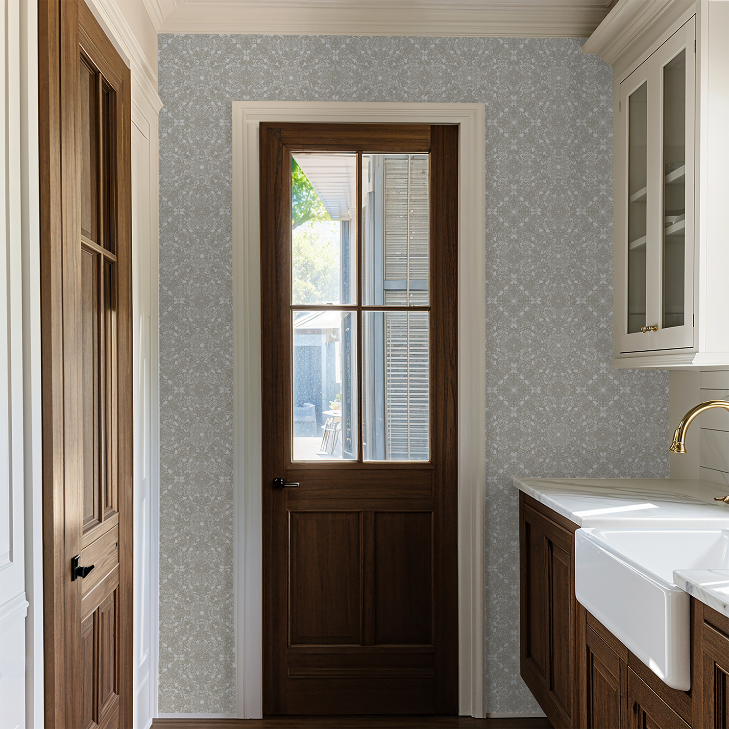 woodland lace mandala style wallpaper in taupe and cream shown in a mudroom interior with wooden doors, sink, and cabinets.