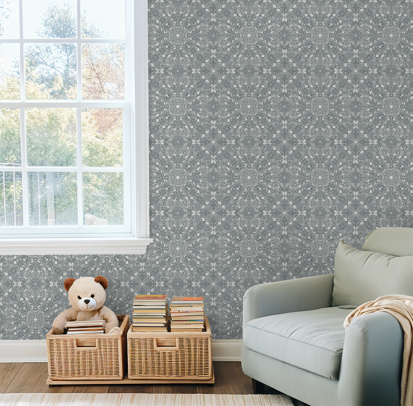 Children’s reading corner with a grey armchair, wicker book baskets, and Woodland Lace in Blue wallpaper beside a bright window.