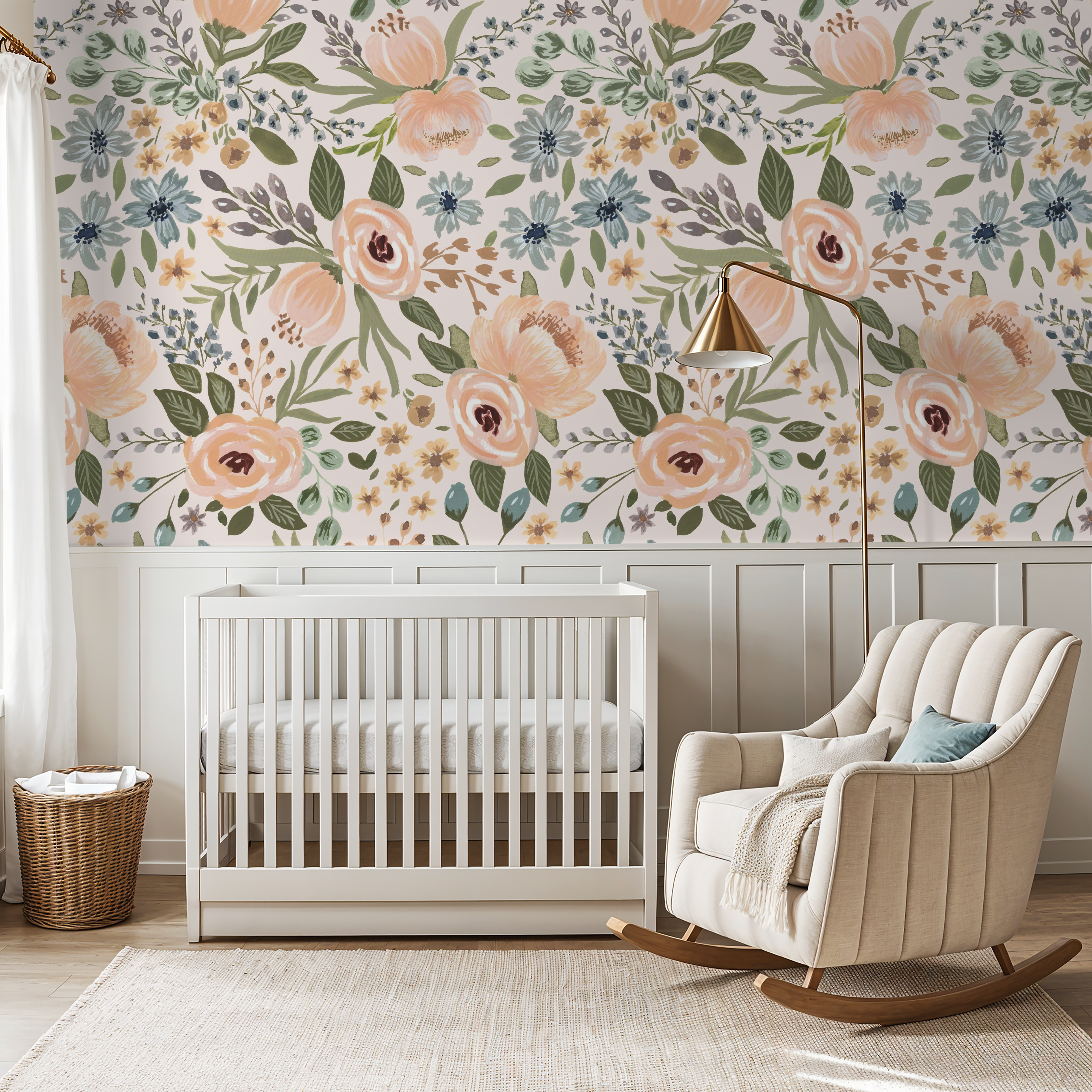Nursery with warm wood wainscoting, cream rocking chair, and crib beneath a feature wall of Juliette’s Summer Blooms watercolor floral wallpaper.