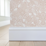 Wallpaper with a subtle floral pattern featuring mushrooms, acorns and foliage in blush pink, applied to a wall corner.