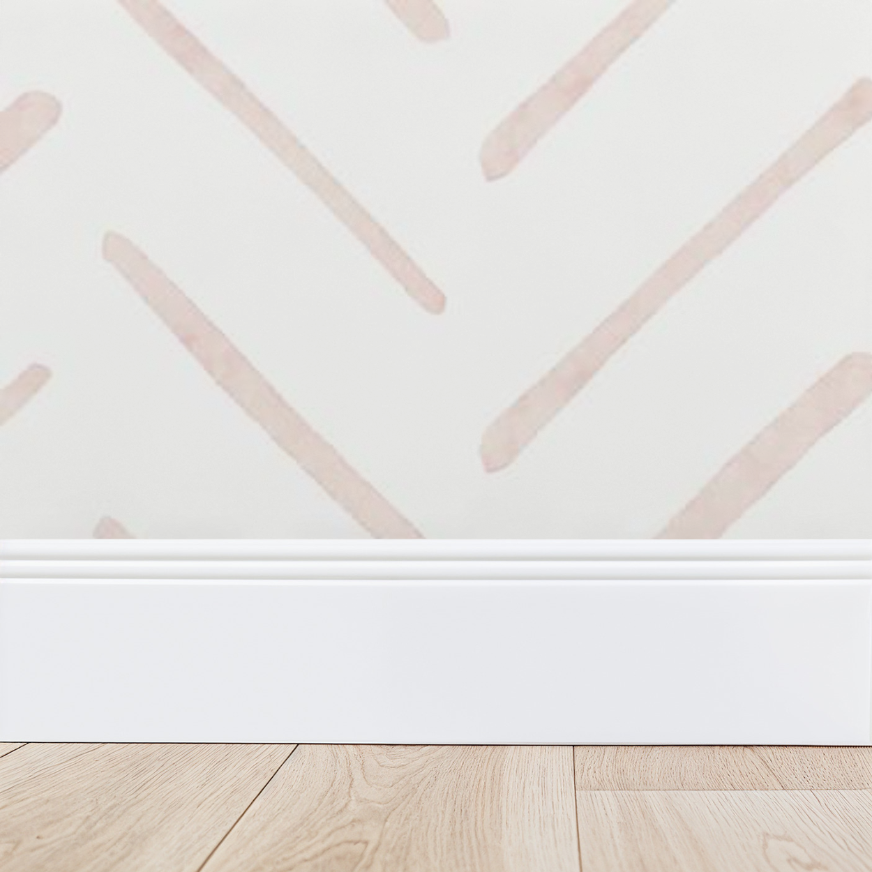 Close-up of blush pink watercolor herringbone wallpaper showing soft hand-painted lines above a white baseboard.