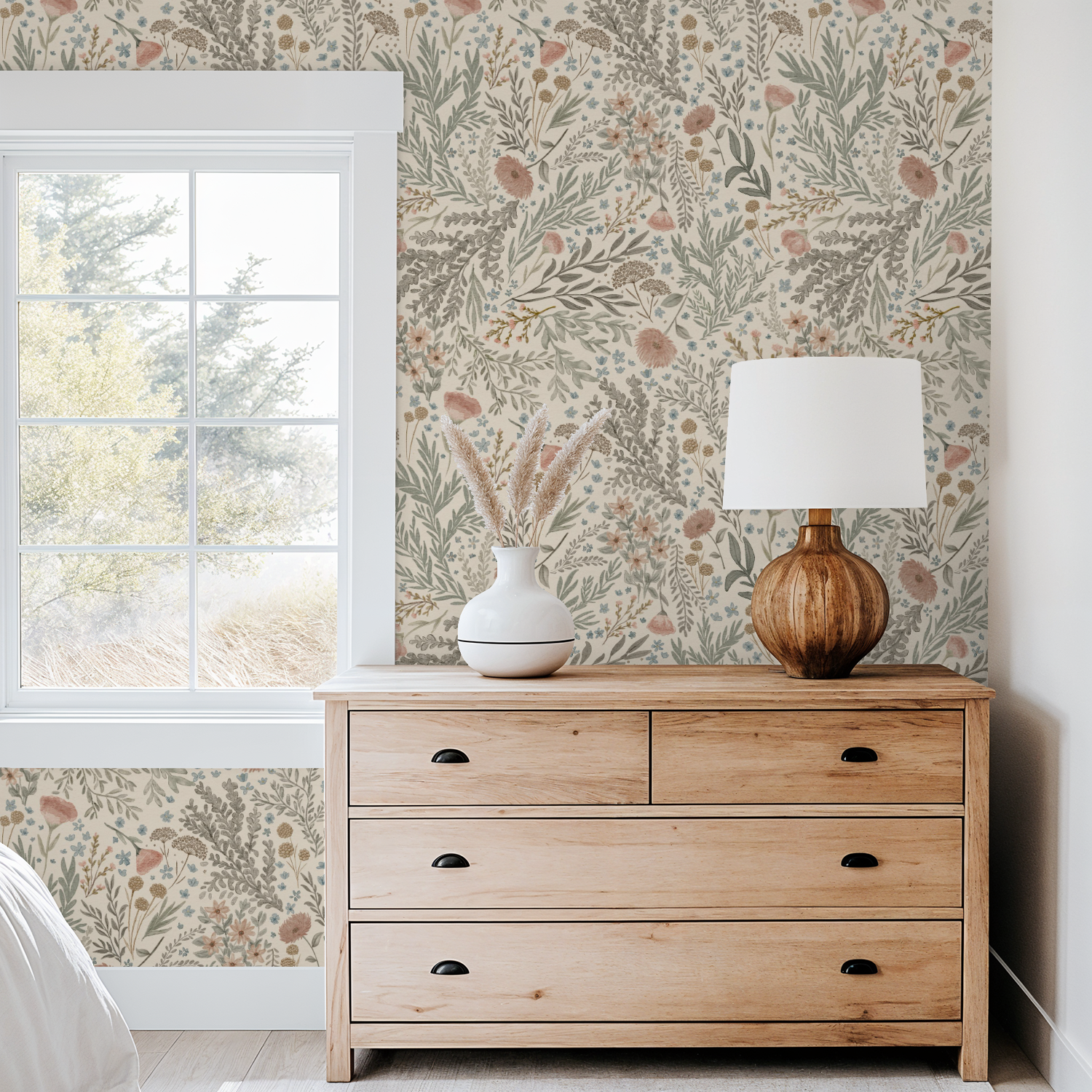 Cozy bedroom corner with a wood dresser and lamp styled against Bronte Woodland Fauna Floral wallpaper in earthy greens and mauve botanicals.