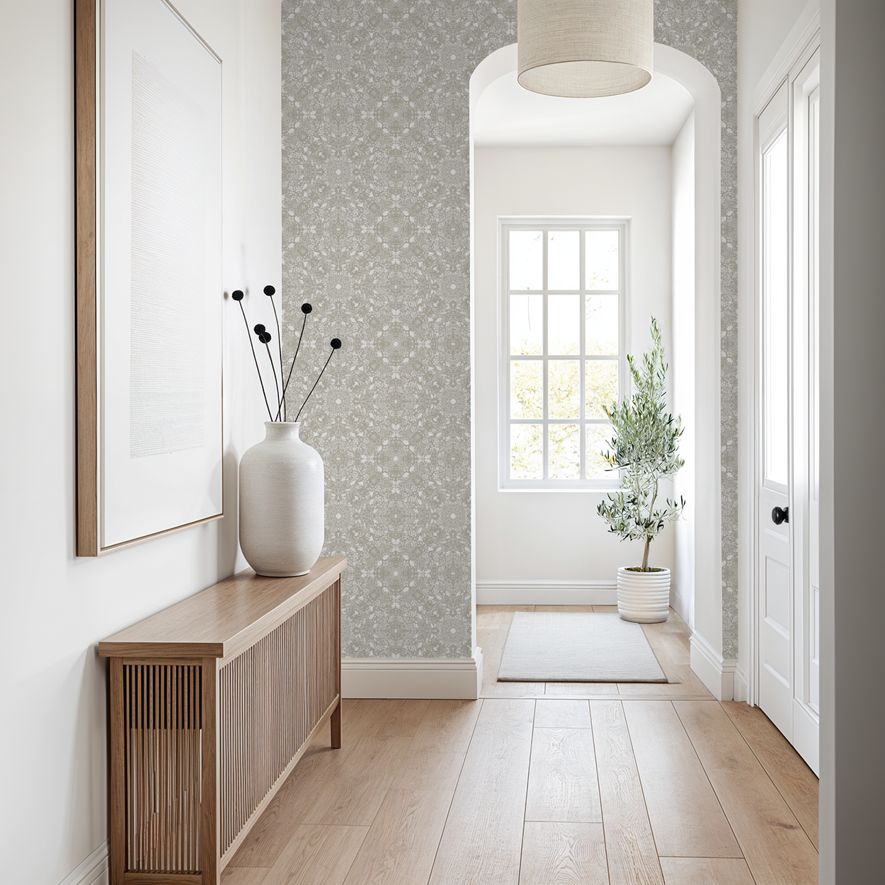 Neutral taupe and cream delicate wallpaper shown around an archway in a Modern hallway with wooden console table, white vase, and framed artwork.
