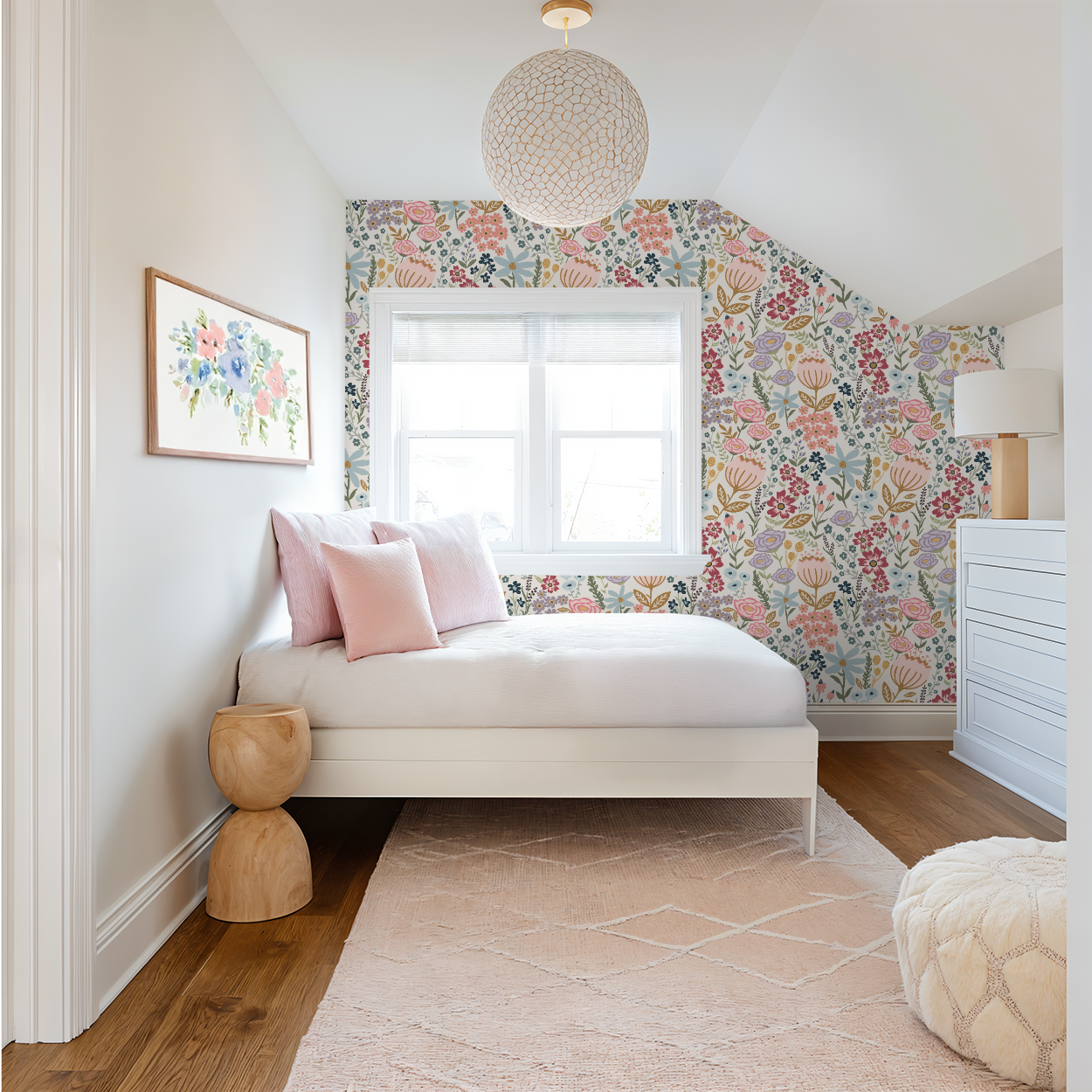 Girls’ bedroom with soft pink pillows and a framed floral print, styled in front of Flo’s Vibrant Garden Party wallpaper.