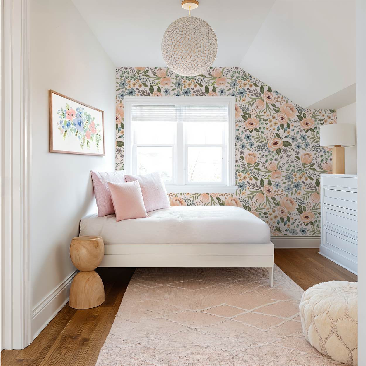 Girls’ bedroom with sloped ceiling, white daybed, and soft pink accents styled against Juliette’s Summer Blooms mural, showing expressive peach and blue hand-painted flowers.