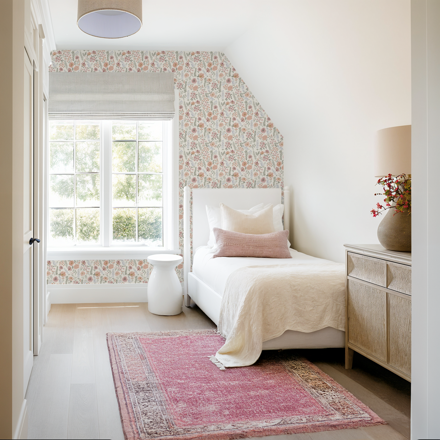 Light and airy bedroom with a single bed and pink accents, framed by Consider the Wildflowers wallpaper in vintage-inspired hues.