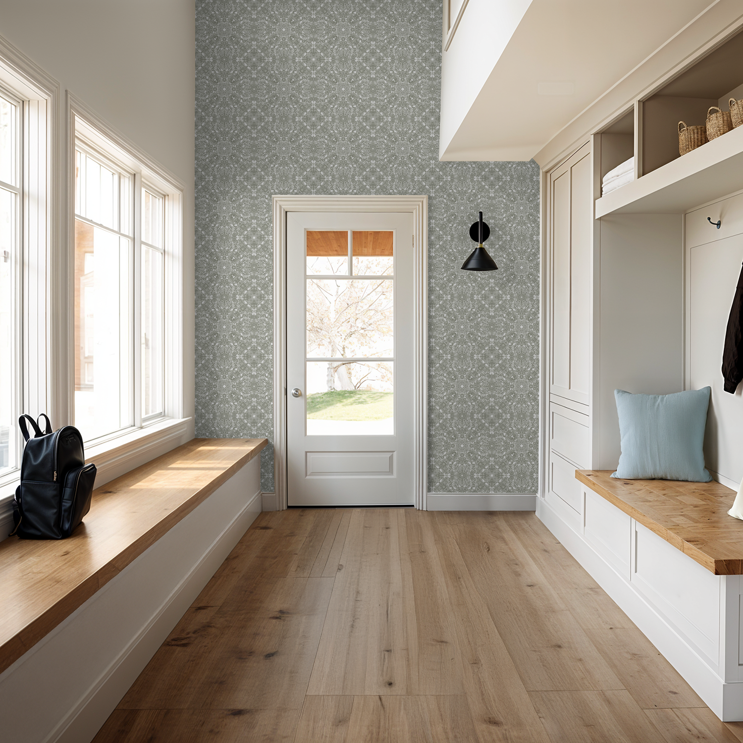 Mudroom with wooden benches, coat hooks, and a door with a Woodland Lace in Sage wallpaper.