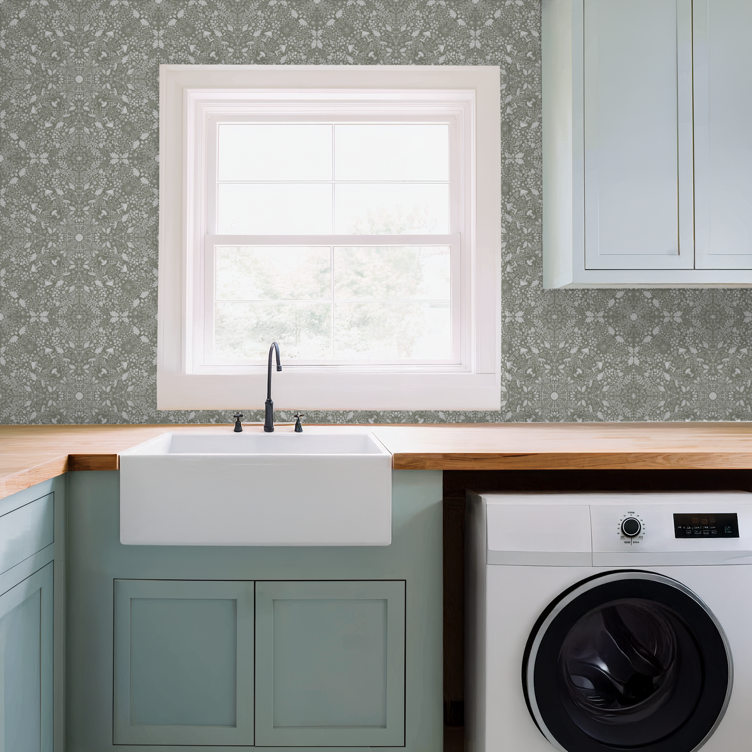 Modern laundry room with a sink and washing machine under a window and a Woodland Lace in Sage wallpaper.