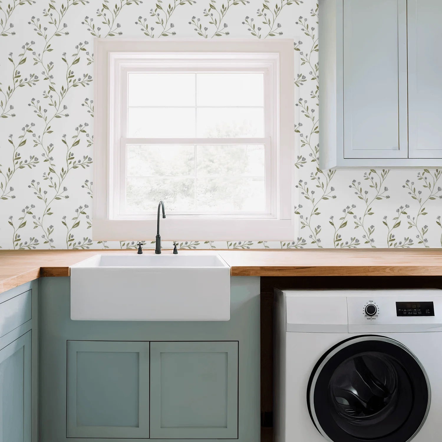 Modern kitchen with a sink, countertop, and washing machine under a window with Tanglewood Trailing wallpaper.