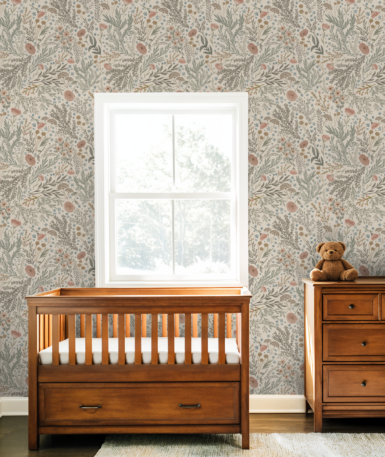 Bronte Woodland Fauna Floral wallpaper in a warm nursery featuring a honey-wood crib, matching dresser, and soft woodland-inspired tones.