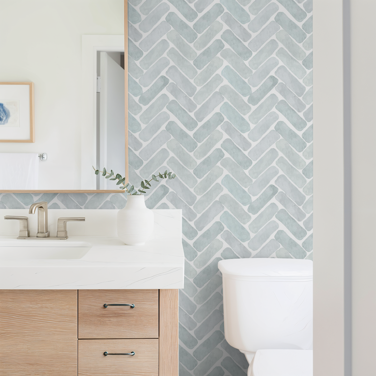 Bathroom with a chevron patterned wall, wooden vanity, and white toilet.