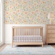 Natural wood crib in a bright nursery with Daisy Spring Dreams wallpaper featuring hand-painted blush daisies.