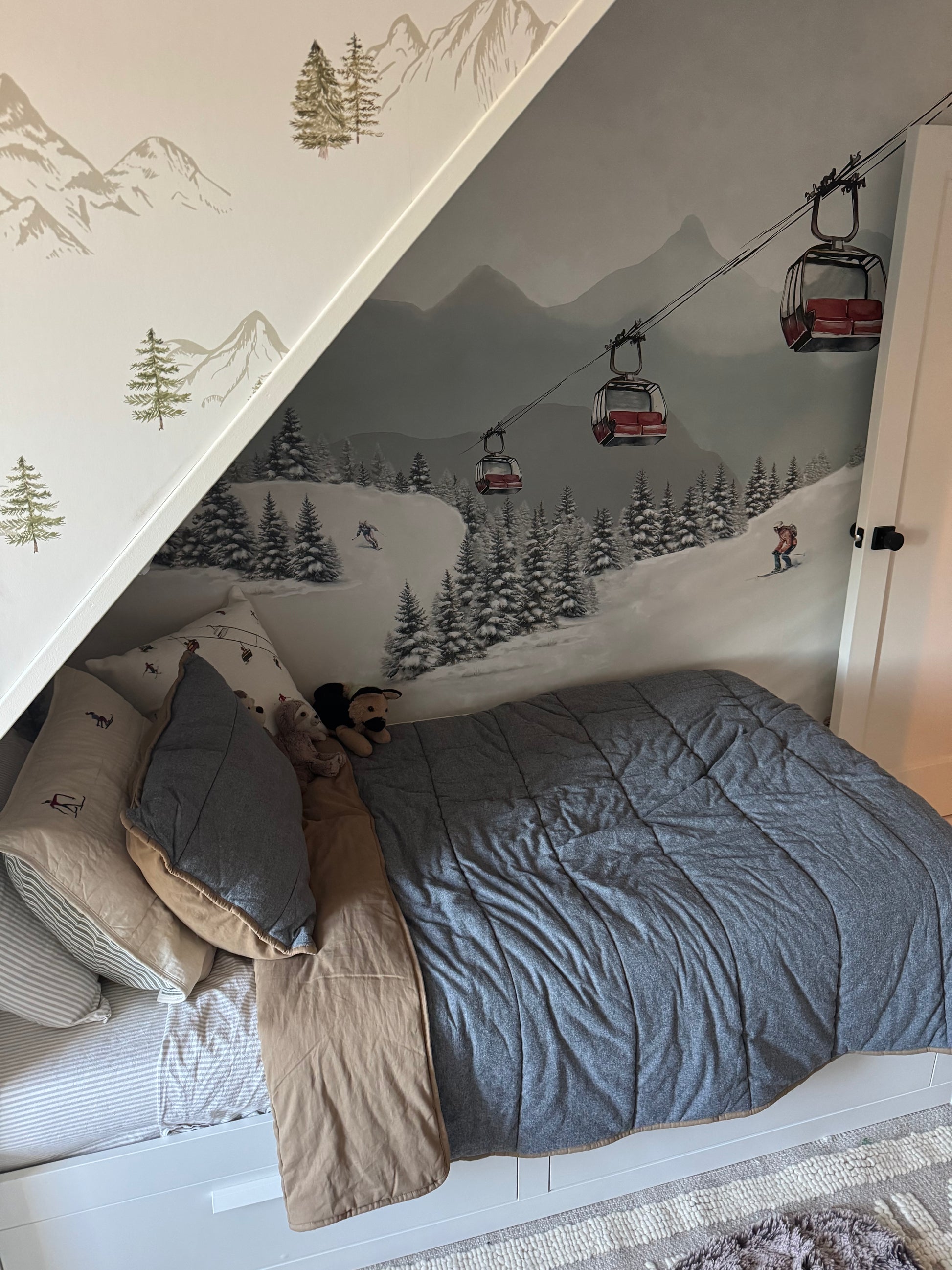 Cozy bed set against the alpine ski mural showing snowy trees, skiers, and red gondola lift chairs.