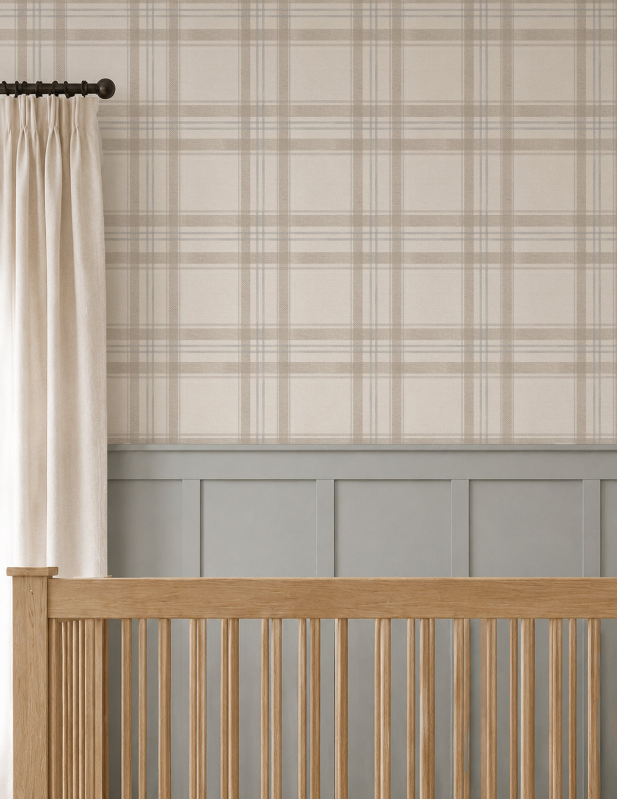 Close-up of London Plaid wallpaper in soft taupe, oatmeal and faded blue above blue-grey nursery wainscoting and a natural wood crib