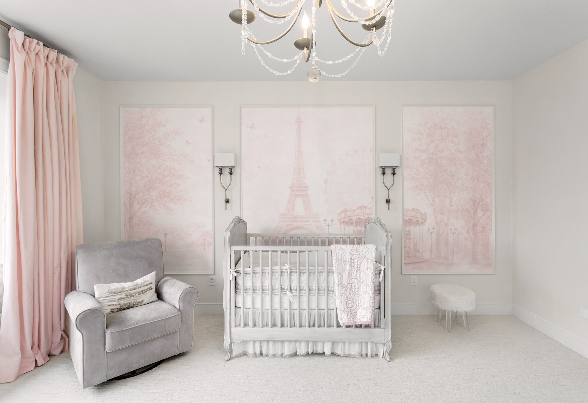 Nursery room with a crib, armchair, and Parisian Dreamscape wallpaper.