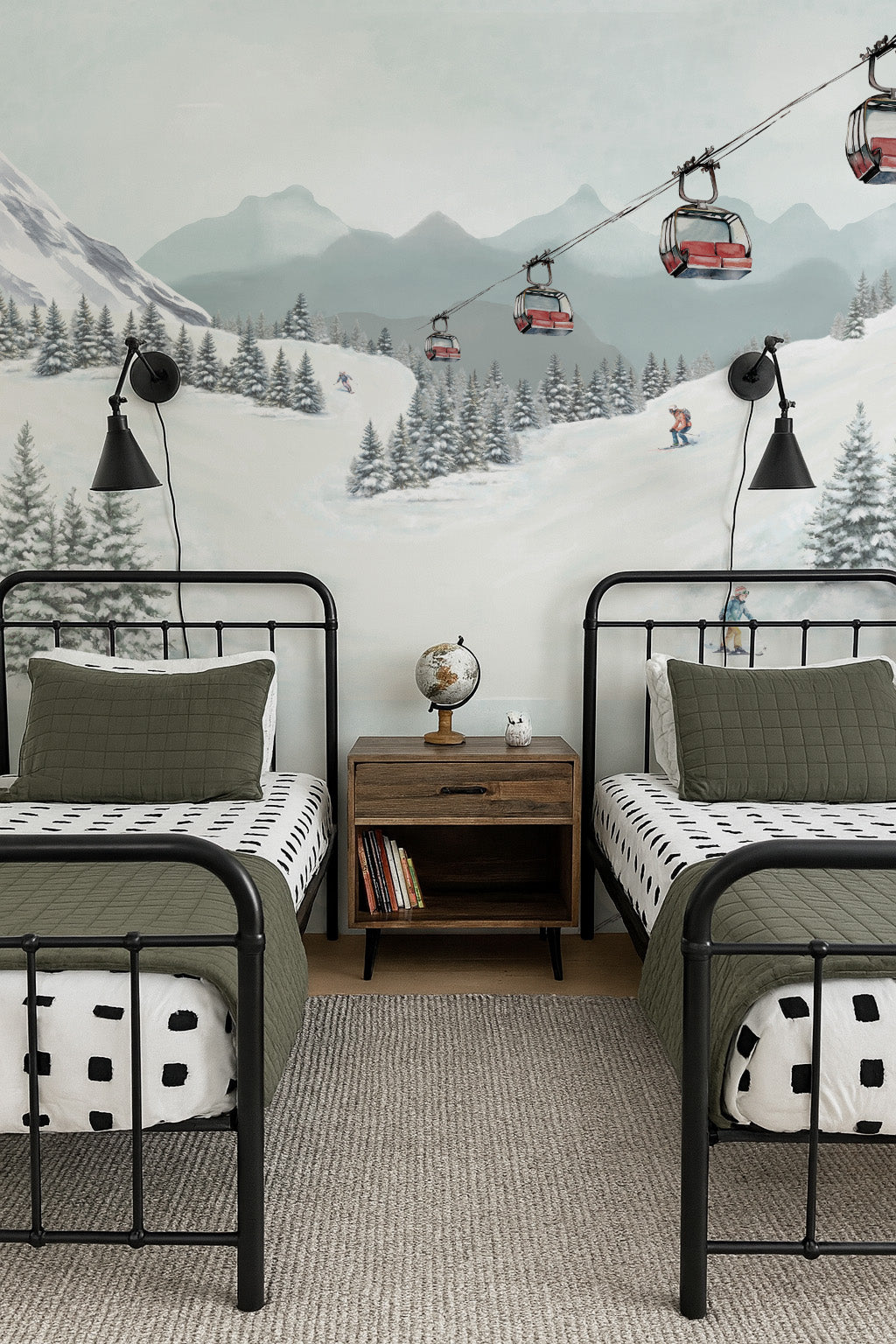 Children's bedroom with two beds, a nightstand, and a mountain mural showing a ski resort and red chairlift.