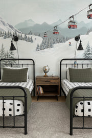 Children's bedroom with two beds, a nightstand, and a mountain mural showing a ski resort and red chairlift.