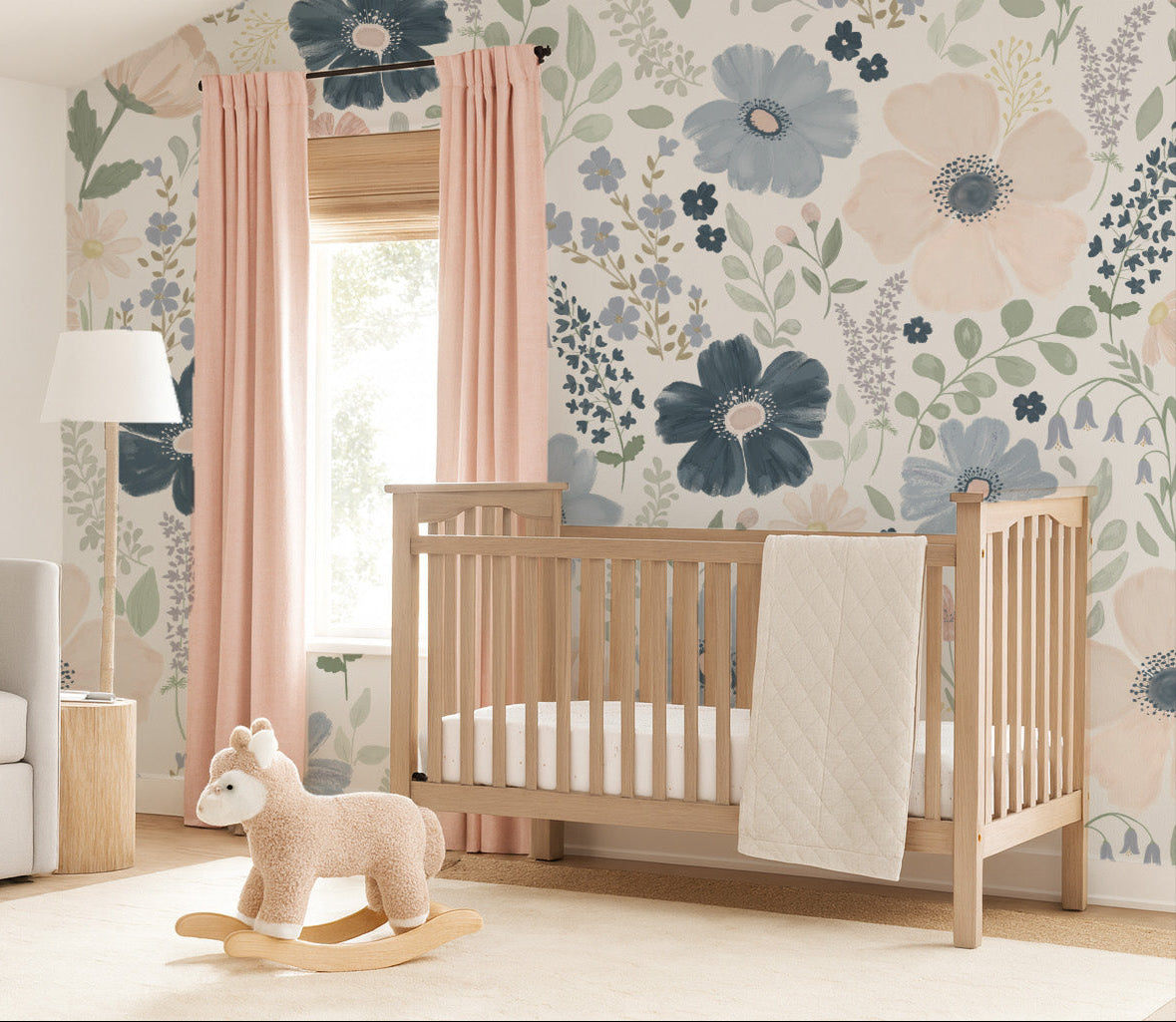 Nursery room with jumbo anenome floral wallpaper in navy, periwinkle and blush pink  with a crib, and rocking horse