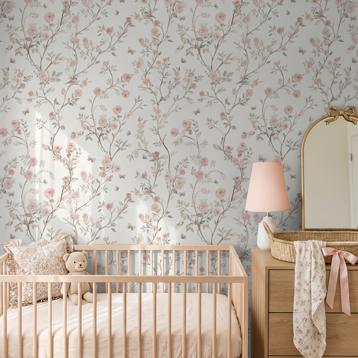 Aurora floral wallpaper featuring pink roses and winding branches behind a wooden crib and nursery dresser.