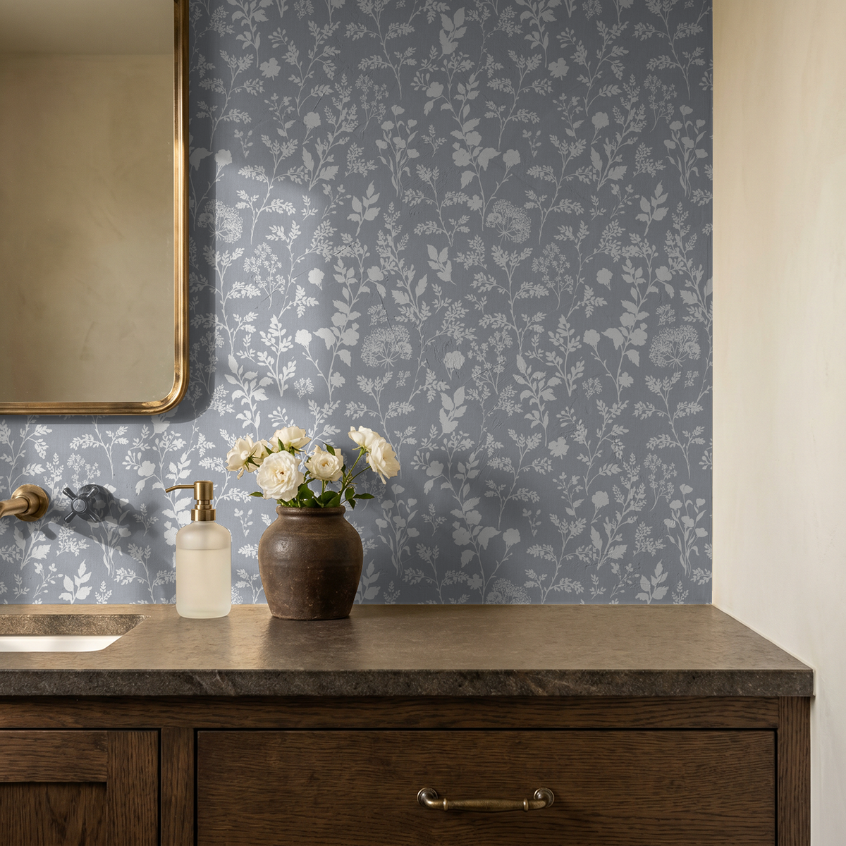 Chambray blue wildflower wallpaper in rustic bathroom setting with wood vanity and vase of flowers.