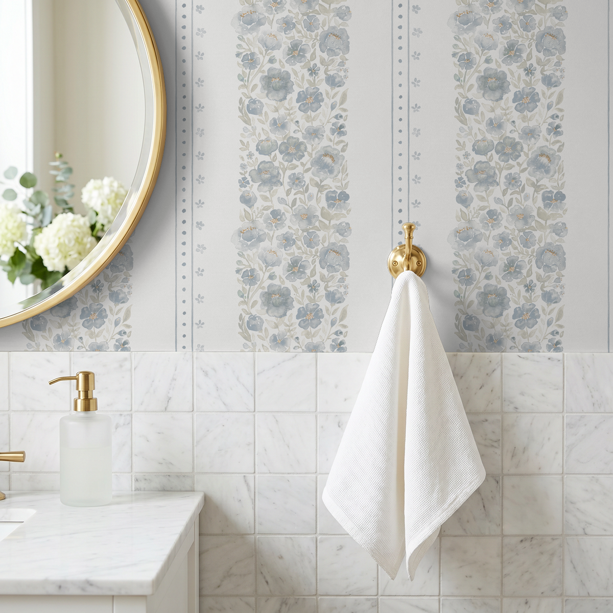 Chambray Cottage blue watercolor floral stripe wallpaper above white marble tile in a light bathroom with brass accents.