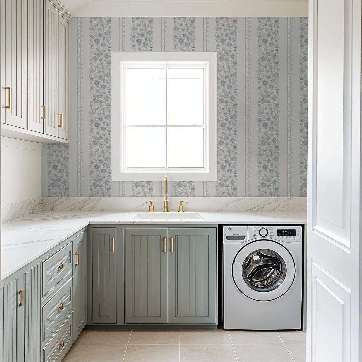 Chambray Cottage blue watercolor floral stripe wallpaper in a bright laundry room with sage green cabinetry and brass hardware.