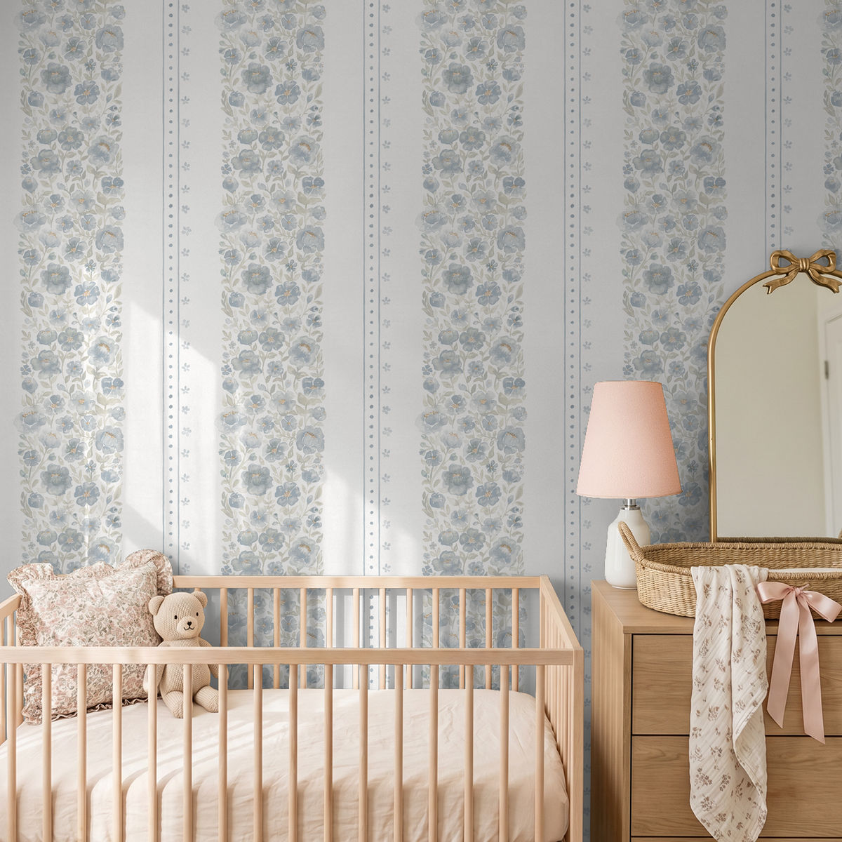 Chambray Cottage blue watercolor floral stripe wallpaper in a soft vintage nursery with natural wood crib and blush accents