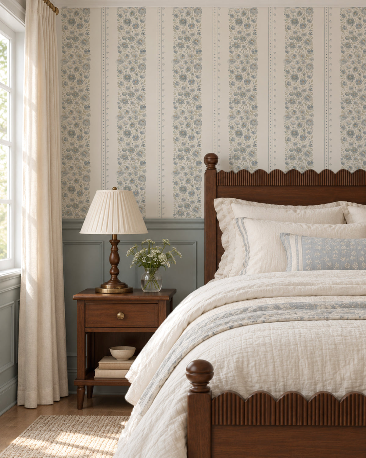 Chambray Cottage blue watercolor floral stripe wallpaper in a soft vintage bedroom with ivory bedding, dusty blue millwork and warm wood furniture.