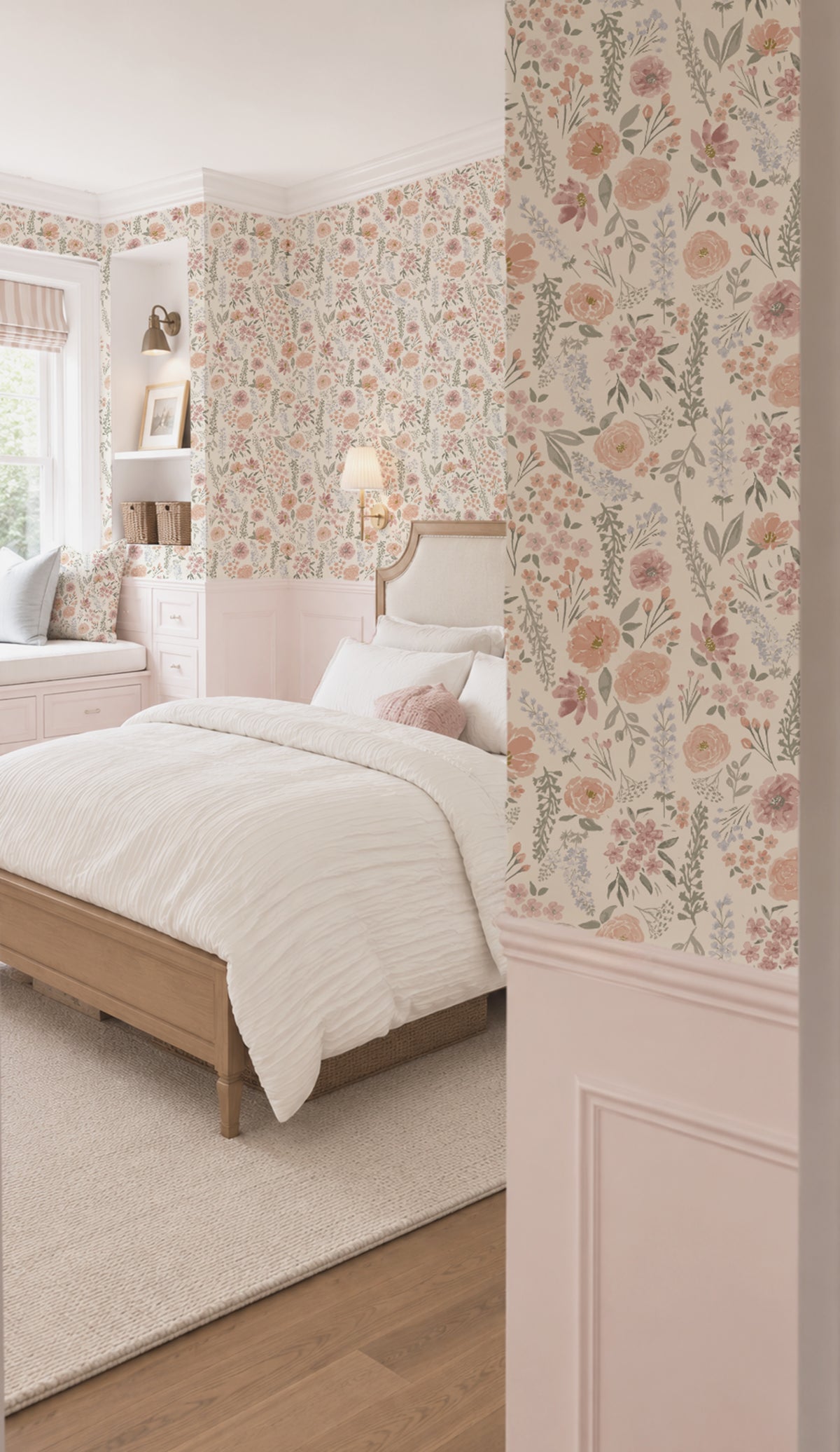 A styled bedroom interior featuring floral wallpaper in soft blush, peach, and sage tones, a light wood bed with white bedding, a cream rug, and pale pink wainscoting.