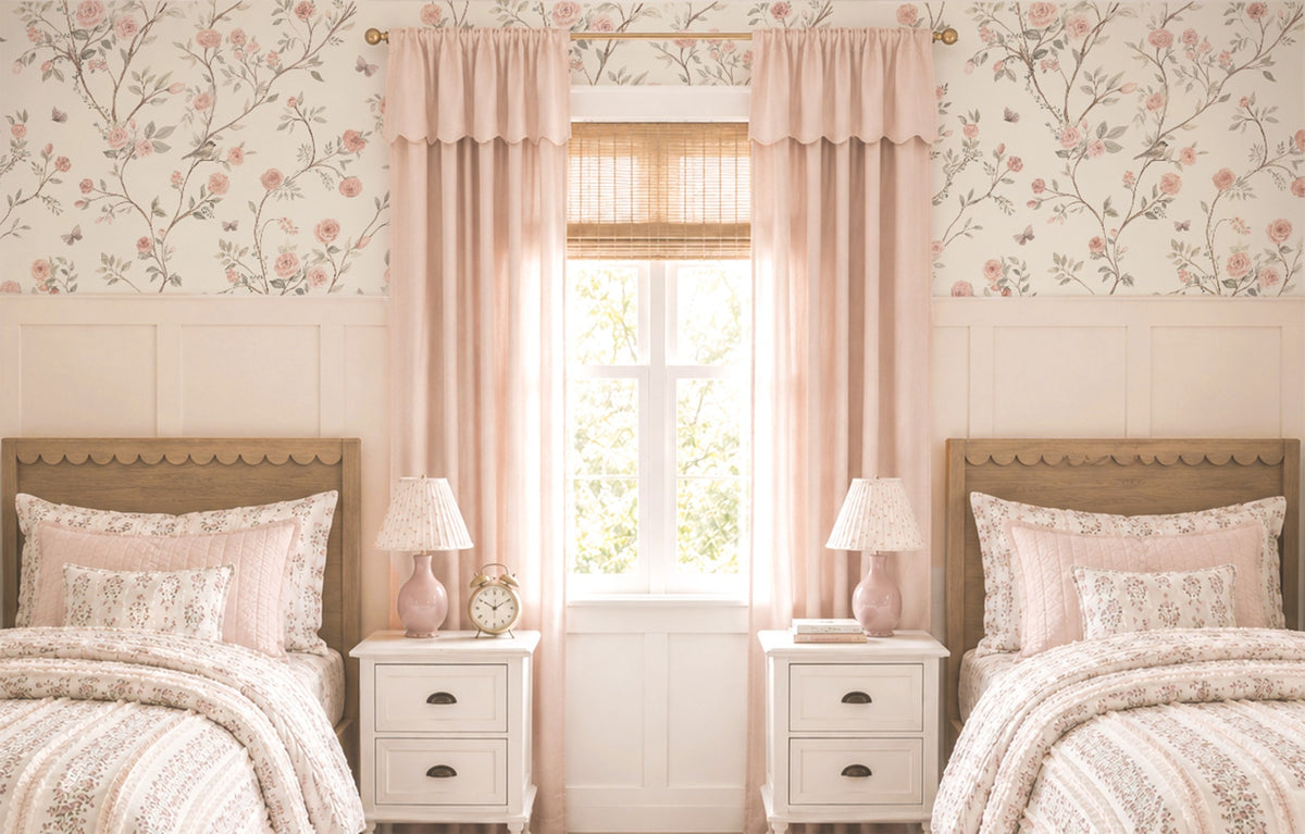 Aurora trailing rose wallpaper in a girls' shared bedroom with twin beds, pink curtains and white wainscoting.