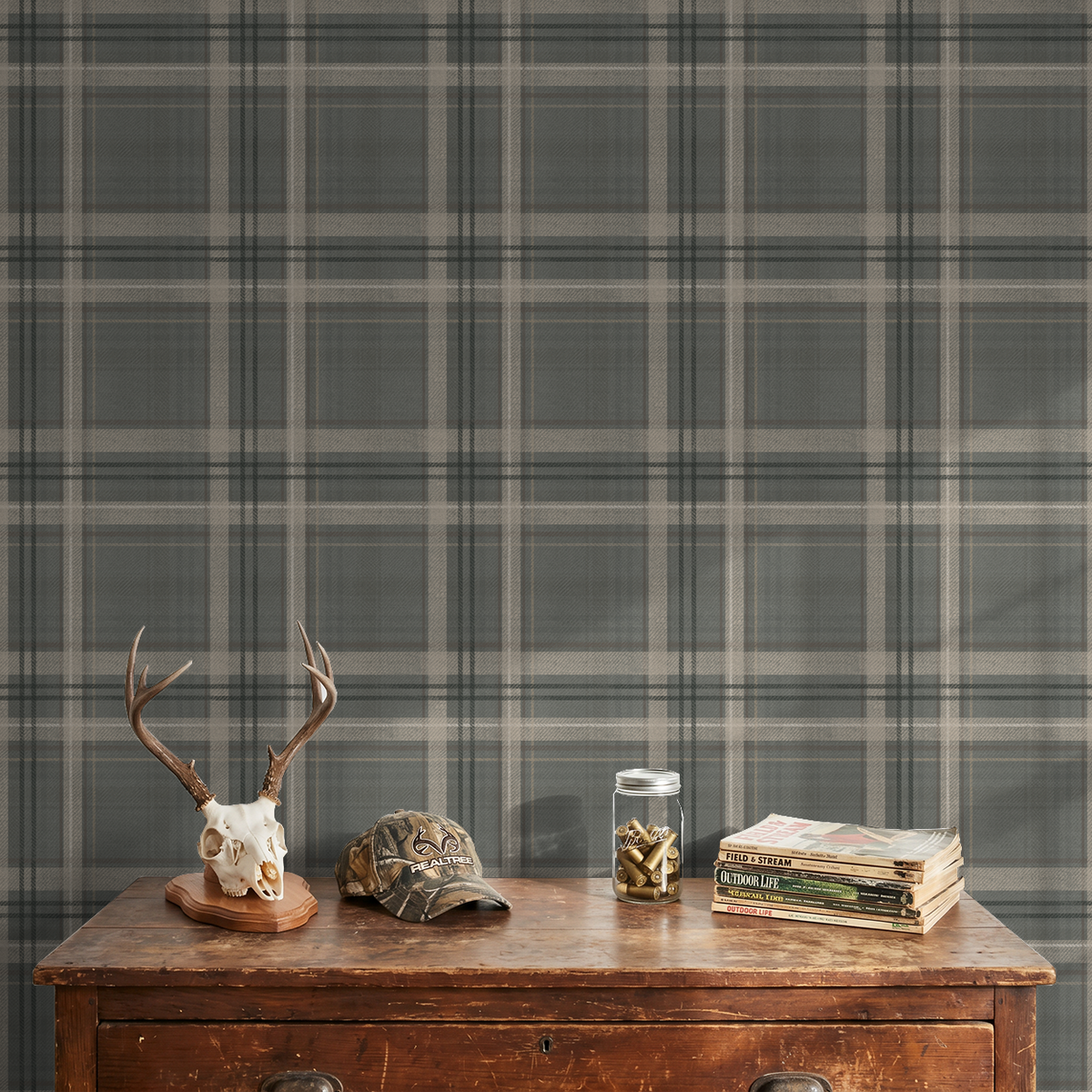 Close-up of Lodge Plaid wallpaper with hunting decor, antlers and outdoor magazines against the grey-green pattern.