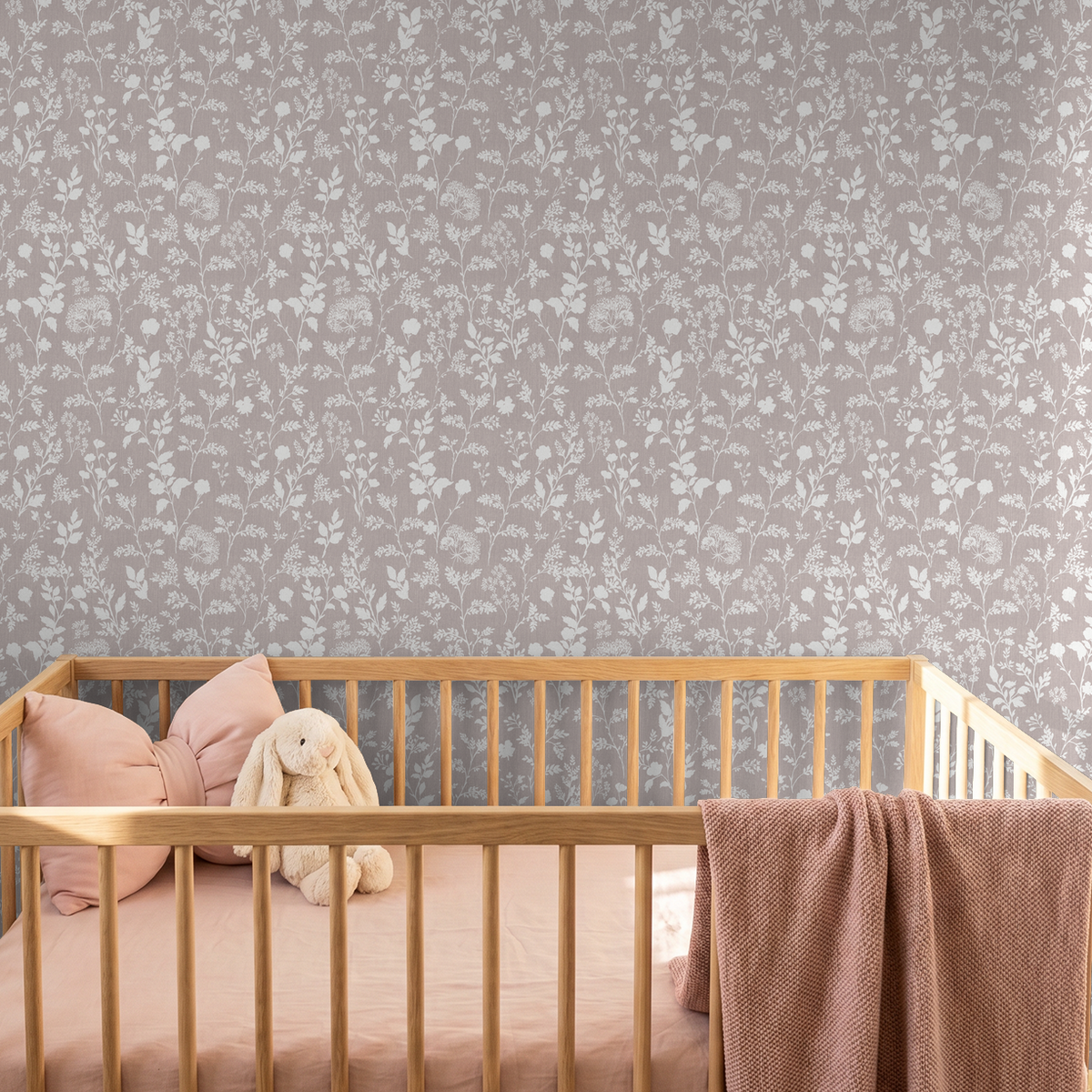 Mauve floral wallpaper with white botanical silhouettes in a nursery setting.