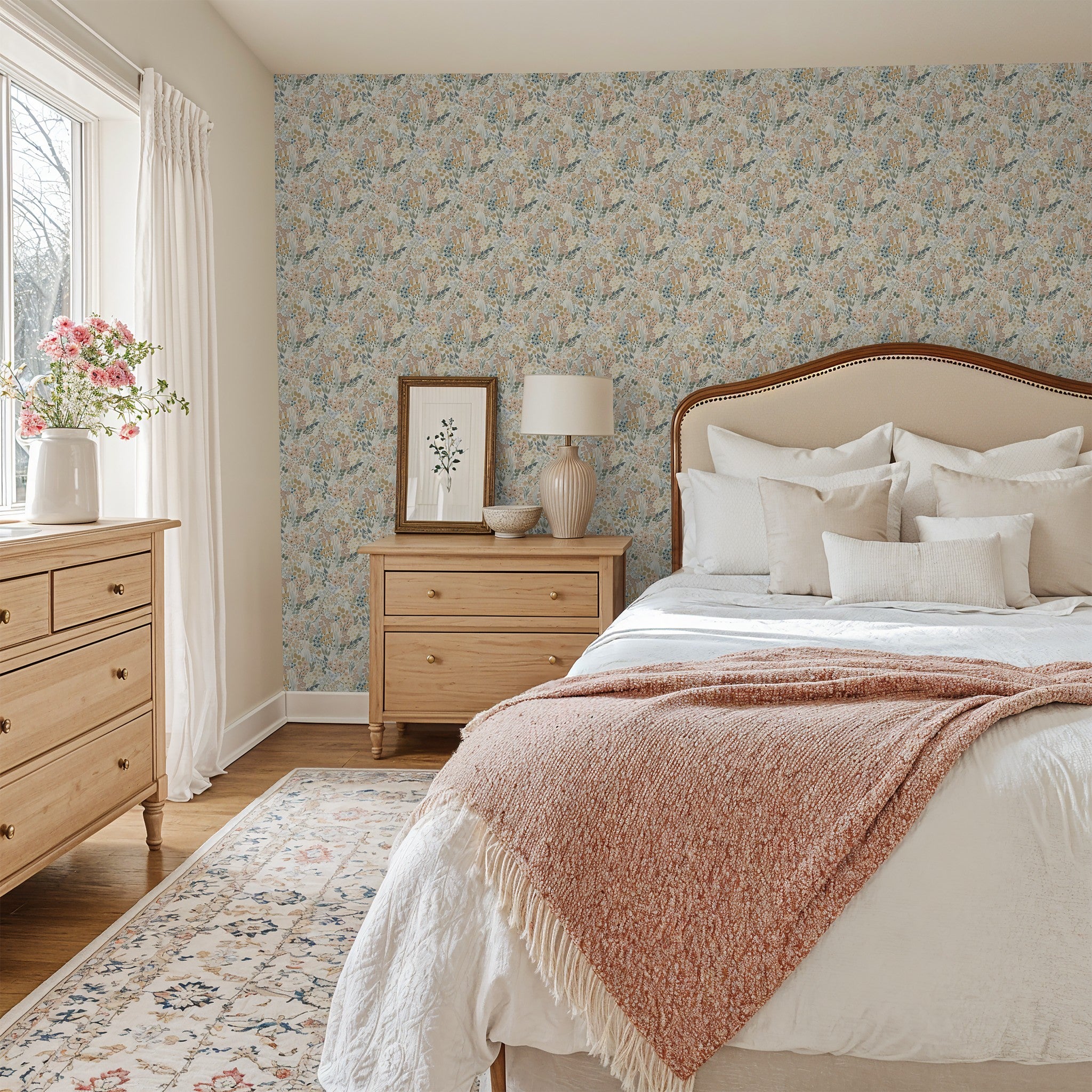 Meadow floral wallpaper in romantic bedroom with warm wood furniture and layered bedding