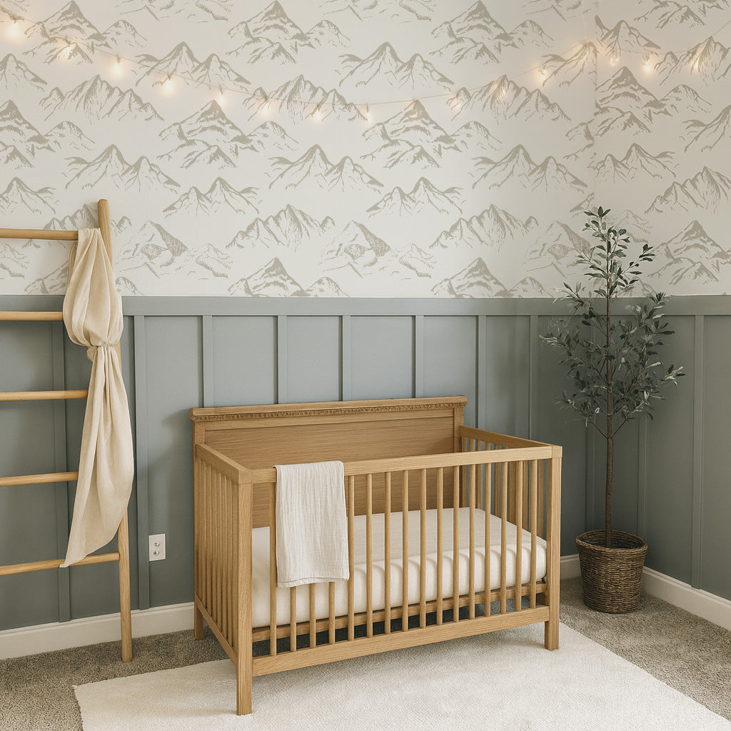 Nursery room with wooden crib, neutral mountain-patterned wallpaper, pannelling and decorative elements.