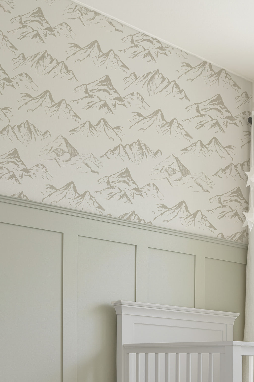 Wallpaper with mountain pattern on a wall with wainscoting and a white crib.