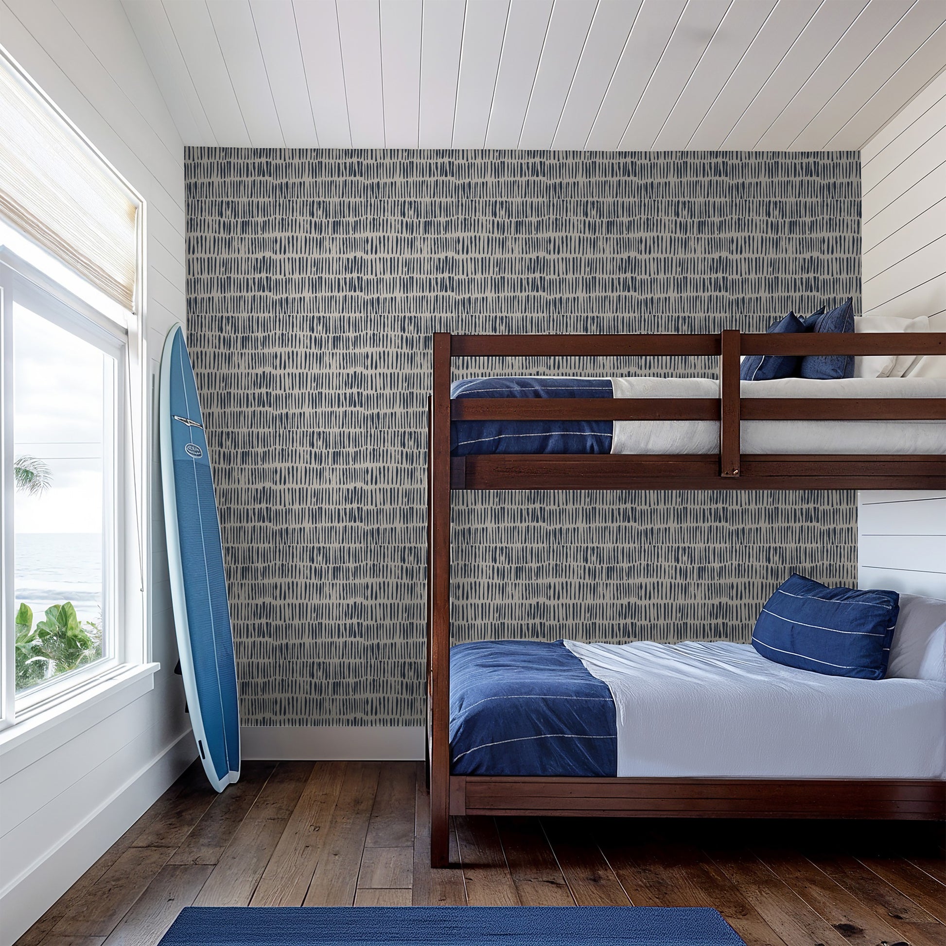 Navy abstract brushstroke wallpaper in coastal bedroom with bunk bed and surfboard.