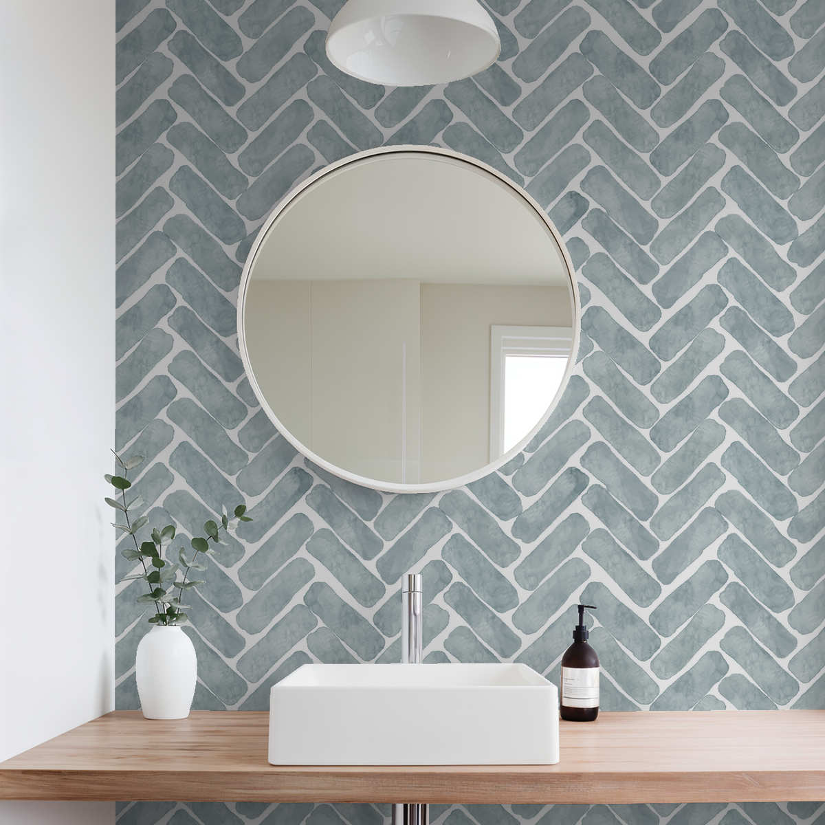 Navy herringbone wallpaper in modern bathroom with round mirror and wooden vanity.