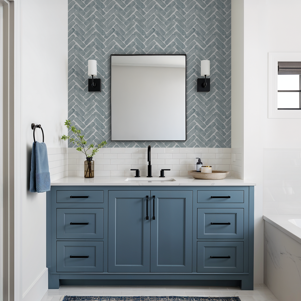 Navy herringbone wallpaper in modern bathroom with blue vanity.